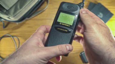MILAN, İTALYA 21 EKİM 2021: 80 'lerden kalma eski bir cep telefonu kullanıyor. 80 'lerin retro masasının üstünden en üst görünüm.