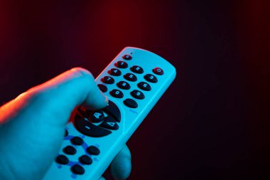Uzaktan kumandayı elinde tut ve vur. Erkek el TV kumandası tutuyor, akıllı bir TV 'de yayınlanıyor..