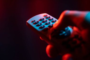 Uzaktan kumandayı elinde tut ve vur. Erkek el TV kumandası tutuyor, akıllı bir TV 'de yayınlanıyor..