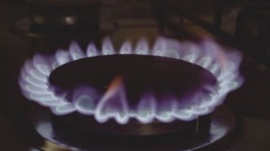 Yanan gaz ocağı yuvası, siyah arka planda mavi alevler makro yakın plan. Gaz açık, mavi alevi yakıyor..
