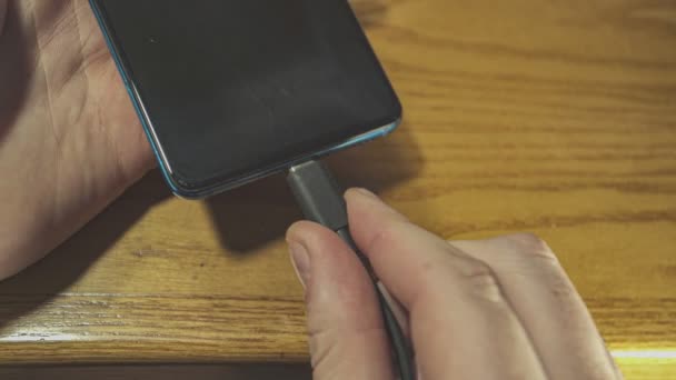 Man Hand Drar Telefonladdaren Sladd Från Smartphone Port Ovanför Träbordet — Stockvideo