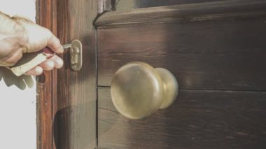 VILLANOVA DEL GHEBBBO, İTALYA 20 Kasım 2021: kapı kilidinde bir anahtar var. El anahtarı alır ve çevirir, sonra kapı açılır..