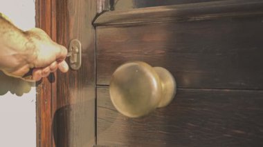 VILLANOVA DEL GHEBBBO, İTALYA 20 Kasım 2021: kapı kilidinde bir anahtar var. El anahtarı alır ve çevirir, sonra kapı açılır..