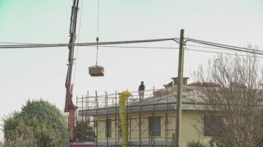 VILLANOVA DEL GHEBBO, İTALYA 29 Kasım 2021: İnşaat işçileri çatı onarımında vinç tamiratı