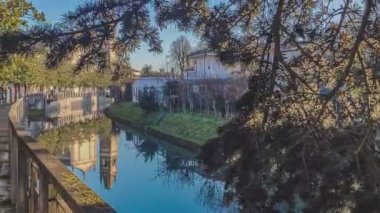 İtalya 'nın Villanova del Ghebbo şehrinde gün batımında bitkiler tarafından filtrelenen Adigetto nehri manzarası. 60 fps atış.