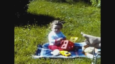 PAVIA, ITALY 21 NİSAN 1969: Bebek 60 'ların aile anılarında çimenlikte oyuncaklarla oynuyor