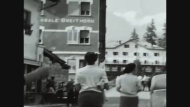 DOLOMITES, ITALY HAZİRAN 1967: 60 'larda evlerin arasından geçen insanlarla Alplerdeki küçük bir köyün sokaktaki günlük hayata bakış