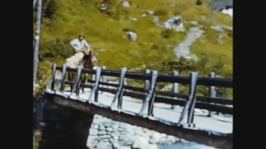DOLOMITES, İTALYA 24 HAZİRAN 1960: 60 'lı yıllarda bir adam köprüde eşeğe biniyor