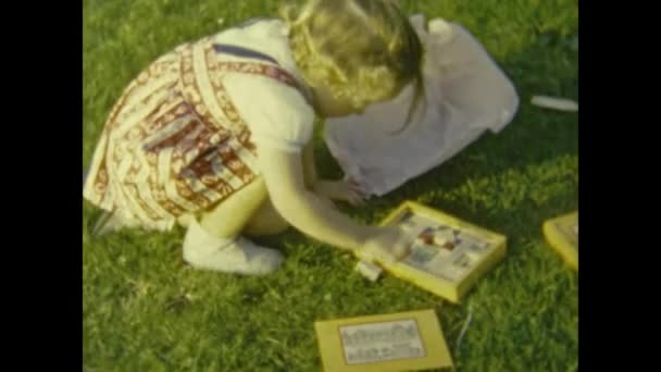 1953年 昭和28年 6月フランス パリ50歳の少女が草の上でおもちゃで遊ぶ — ストック動画