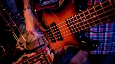 Bir erkek bas gitarist sahnede canlı performans sırasında bas çalar.