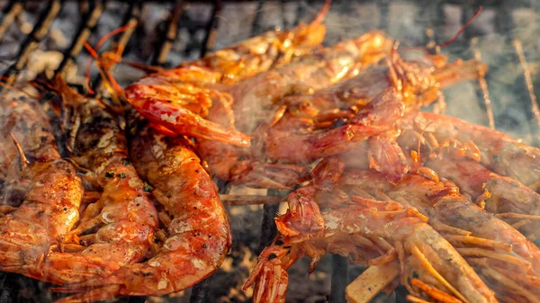 Grilled shrimp on a grill with charcoal grill. Close-up of shrimps being fried in oil pan