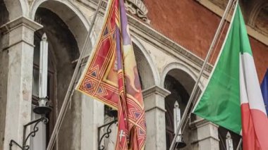 Italian and European flags on the historic building of Town Hall of Rovigo. Slow motion.