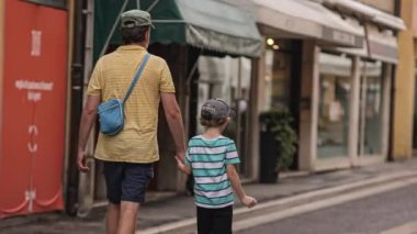 Rovigo, Italy 08 August 2022: Dad and child walk city hand by hand