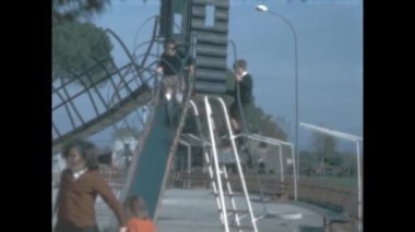 Assisi, Italy june 1965: Children slide at the park scene in 60s