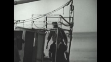 Catanzaro, Italy august 1962: Small fishing boats on the beach fisherman sew net in 60s