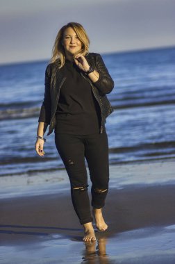 Genç sarışın kız bir sonbahar günü sahilde geziniyor..