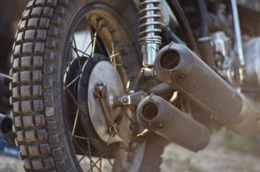 Arka tekerleğin ayrıntıları ve eski bir motosikletin egzozu ileri derecede yıpranmış..