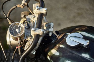 Gidonun ayrıntıları ve klasik siyah motosikletin hız göstergesi görünür krom ve kontrol detaylarıyla birlikte..