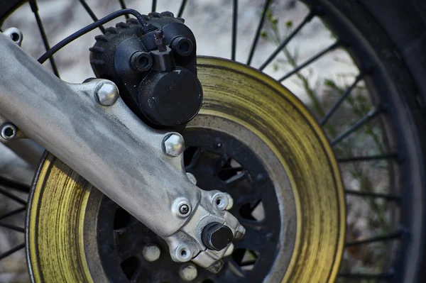 Kalibreli ve çatallı bir disk freninin ayrıntıları eski model bir motosikletin tekerleğine monte edilmiş..