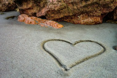 Bozulmamış kumsalın kumlarına çizilmiş bir kalp: Gerçekten sevenler için tatlı ve şiirsel bir sevgi jesti