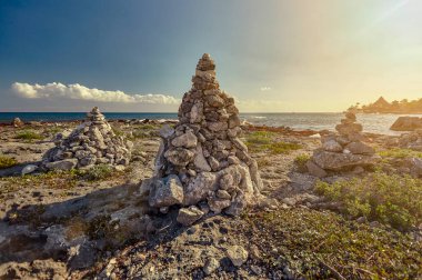 Puerto Aventuras 'ın kayalık sahillerinde gün batımında Meksika' da Maya Rivierası 'nda Zen kayaları yığılıyor..