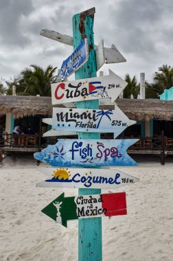 Sign with wooden arrows and blue, containing indications for cuba, florida, cozumel, ciudad de mexico and fish spa