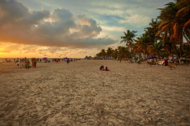 Isla Mujeres plajının manzarası. Denizin üzerinde günbatımının tadını çıkarmak isteyen insanlarla doluyken.
