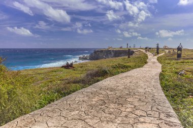 Taştan yol, denizin arka planına sahip yeşil bir bahçeyi geçer: Meksika 'daki Isla Mujeres' deki panorama