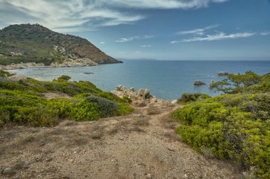 İçine tepeler ve yeşil çalılar çevrili Akdeniz güzel bir körfezde açar küçük toprak yol.