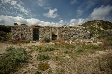 Sardunya olan güneydeki tepenin ortasında terk edilmiş eski taş bina: yalnızlık ve terk edilme sembolü.