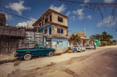 Tulum, Mexico 20 august 2022: Small ruined house is the background of a dirt road and an elderly man walks: Moments of everyday life in Tulum, Mexico