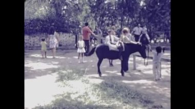 Santa Maria, Peru Haziran 1974: Turistler ve çocuklar 70 'lerde bir tatil beldesinde at ahırında eğleniyorlar