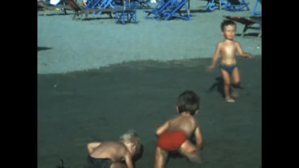 エルバ島 イタリア1971年6月 小さな子供たちがビーチの休暇のシーンで砂の上で遊ぶ 70年代の海の休暇の家族の思い出 — ストック動画