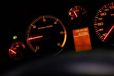Karanlıkta kırmızı araba takometresi. Hızın sembolü. Gösterge paneli hız göstergesi, takometre, kilometre sayacı. Araba tamiri. Araba konsolu. Gösterge paneli lambaları ile ilgili detaylar. Araç enstrüman paneli