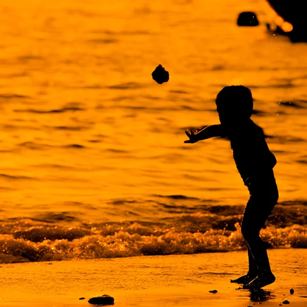 Силуэт маленького ребенка на пляже на закате — стоковое фото