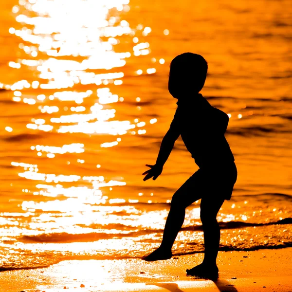 Силуэт маленького ребенка на пляже на закате — стоковое фото