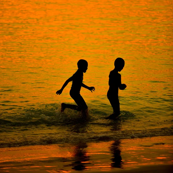 Küçük çocuk bir plaj gün batımında siluet — Stok fotoğraf