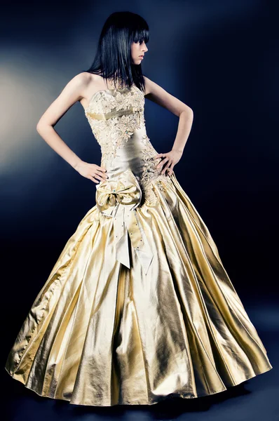 Flicka i ett guld klänning på en svart bakgrund Royaltyfria Stockfoton