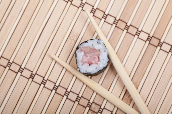 Closeup sushi en eetstokjes op bamboe mat — Stockfoto