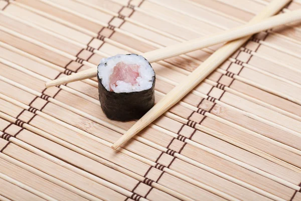 Closeup sushi en eetstokjes op bamboe mat — Stockfoto