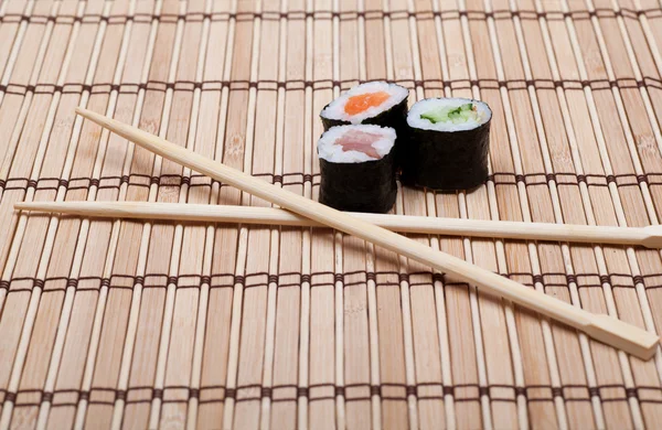 Sushi en eetstokjes op bamboe mat — Stockfoto