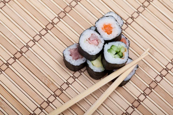 Closeup sushi en eetstokjes op bamboe mat — Stockfoto