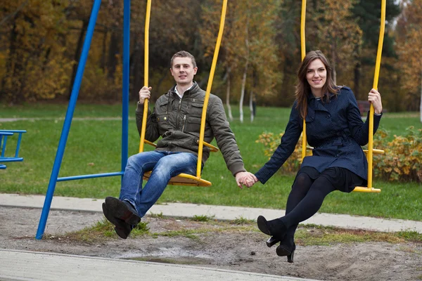 Молодая пара в парке на качелях — стоковое фото