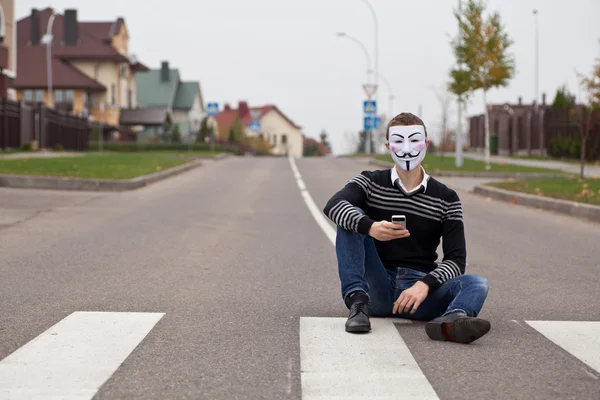 Hacker em membros mascarados do Anônimo com telefone celular — Fotografia de Stock