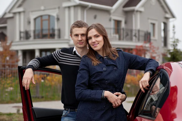 Giovane famiglia vicino auto su sfondo casa — Foto Stock