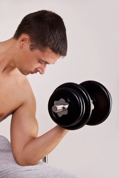 Handsome man uses dumbbells — Stock Photo, Image