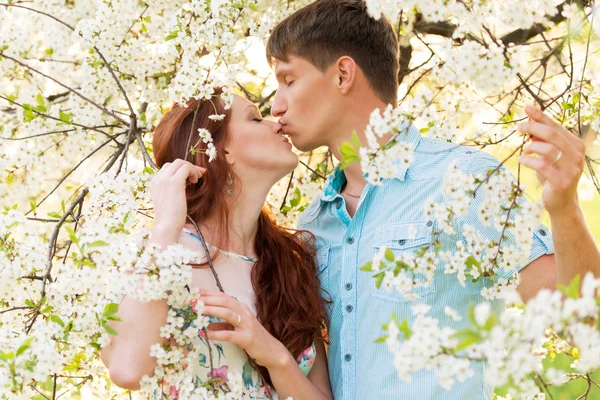 Kissing lovely couple in flower garden — Stock Photo, Image