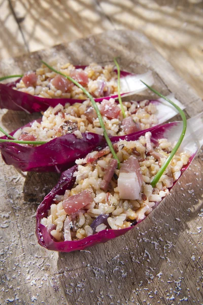 Båt av brunt ris med röda radicchio och speck — Stockfoto