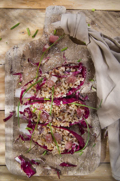 Båt av brunt ris med röda radicchio och speck — Stockfoto