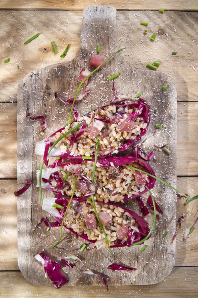 Boat of brown rice with red radicchio and speck — Stock Photo, Image